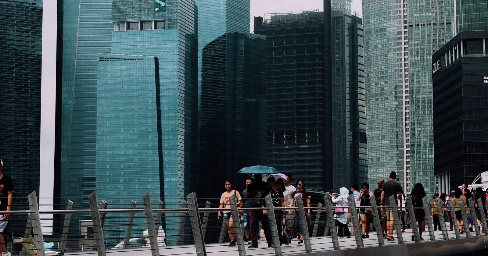 Gente cruzando un puente frente a las torres del distrito financiero de Singapur